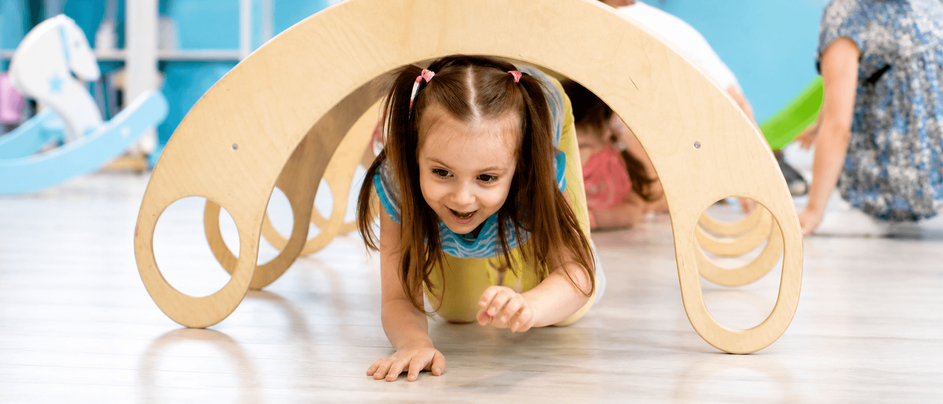 A child crawling through a wooden play arch